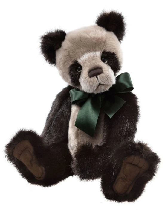 Stuffed panda bear with a green bow tie on a plain background